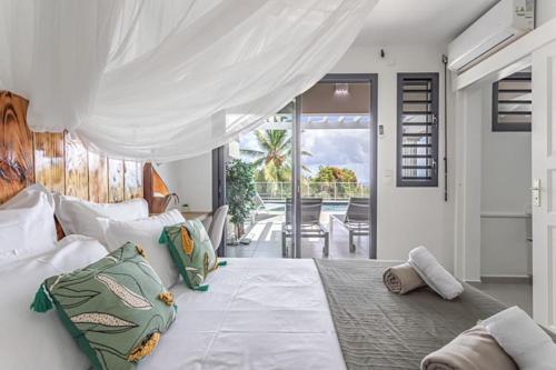 a bedroom with a large white bed with pillows at VILLA MELINA in Cadet