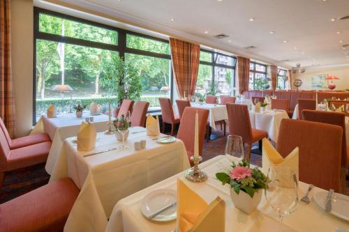 漢堡的住宿－貝斯維斯特漢堡國際酒店，餐厅设有白色的桌椅和大窗户。