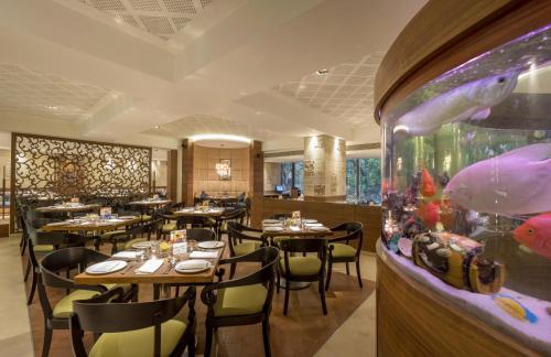 a restaurant with tables and chairs and a fish tank at The International by Tunga in Mumbai