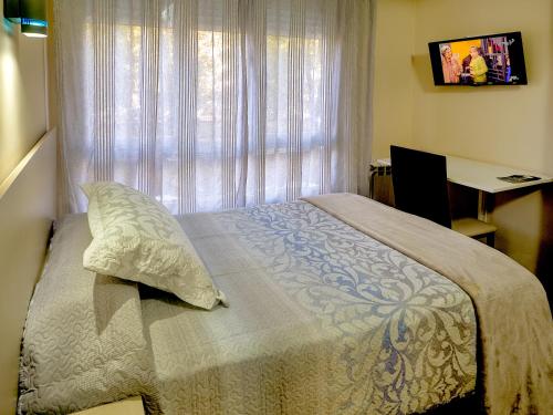 a bedroom with a bed with a window and a desk at Hostal Real Aranjuez in Aranjuez