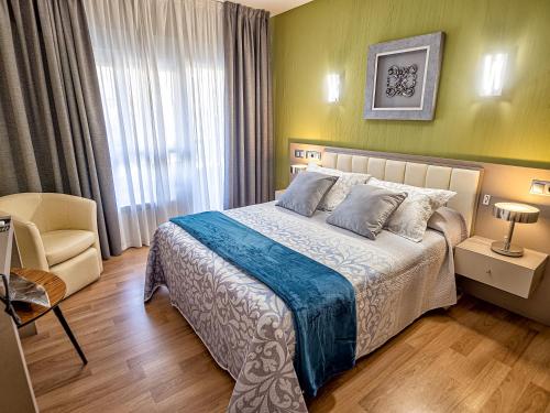 a bedroom with a bed and a chair and a window at Hostal Real Aranjuez in Aranjuez