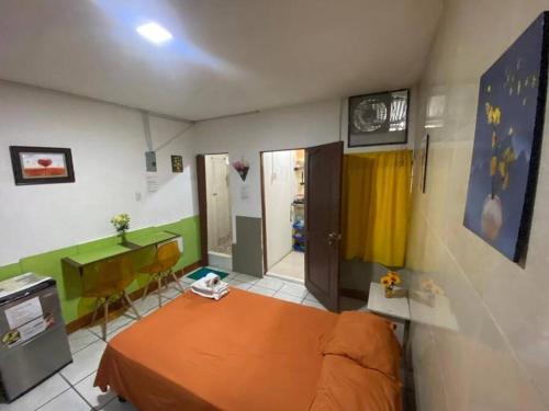 1 dormitorio con cama de color naranja y escritorio en Mini Suite Independiente en Garzota Norte, en Guayaquil