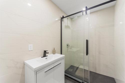 a white bathroom with a sink and a shower at Stonewall Suites in Montréal