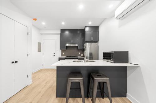 a kitchen with a counter with stools and a microwave at Stonewall Suites in Montréal