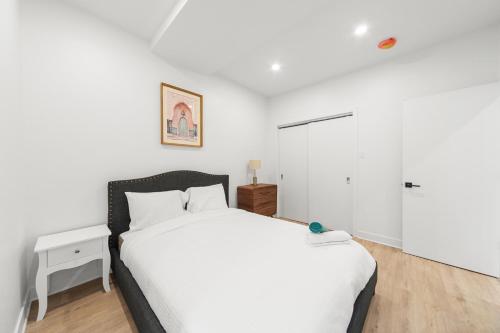 a bedroom with a white bed and a white cabinet at Stonewall Suites in Montréal