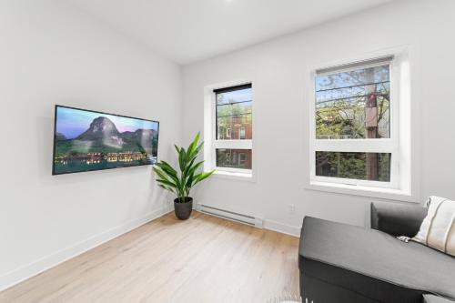 a living room with a couch and two windows at Stonewall Suites in Montréal