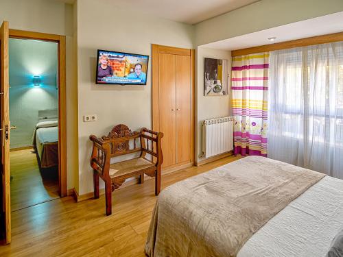 a bedroom with a bed and a tv on the wall at Hostal Real Aranjuez in Aranjuez