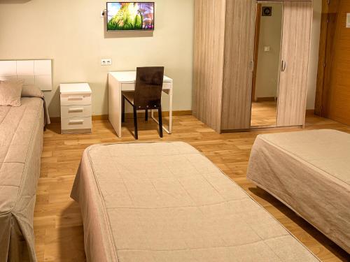 a bedroom with two beds and a table with a chair at Hostal Real Aranjuez in Aranjuez