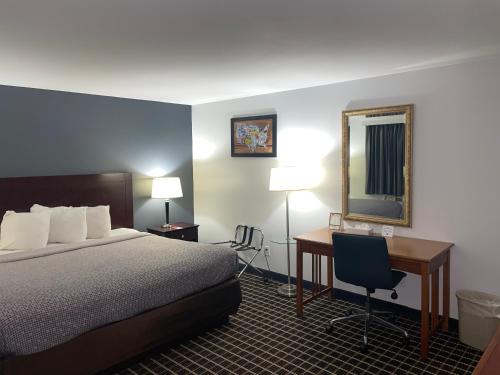 ein Hotelzimmer mit einem Bett, einem Schreibtisch und einem Spiegel in der Unterkunft Econo Lodge Jefferson Hills Hwy 51 in Clairton