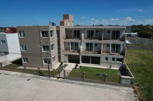 Un edificio de apartamentos con césped delante. en Solana - Apart Hotel & Club de Tenis, en Santa Clara del Mar