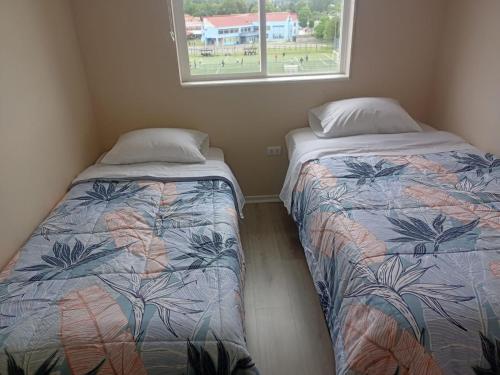 two beds in a small room with a window at Brisas del sur in Osorno