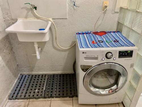 uma máquina de lavar roupa na casa de banho com um lavatório em 3 Quartos Melhor Valor do Df próximo ao Aeroporto e Plano em Brasília