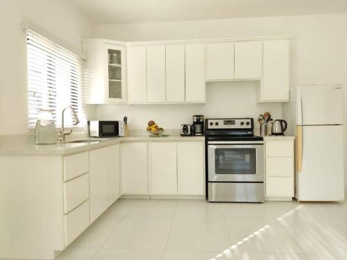 cocina blanca con armarios blancos y nevera en The Willow Apartment, en Clifton Falls