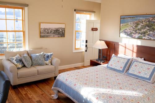 a bedroom with a bed and a couch and windows at 14 1/2 St. George Street in Saint Augustine