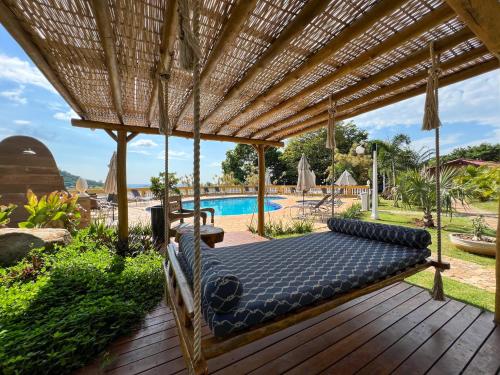 een bed op een houten terras met een zwembad bij Pousada Vale do Dinossauro in São Pedro
