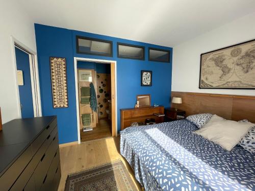 ein Schlafzimmer mit einer blauen Wand und einem Bett in der Unterkunft Une grande terrasse sur la mer in Brando