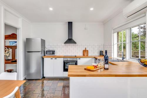 uma cozinha com electrodomésticos brancos e uma bancada de madeira em Hahndorf Creek Retreat em Hahndorf