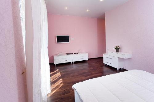 カザンにあるApartments near Metro Station Sukonnaya Slobodaのピンクの壁のベッドルーム(ベッド1台、テレビ付)