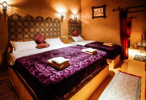 a bedroom with two beds with purple sheets at Dar marco polo in Erfoud