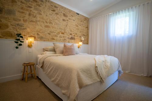a bedroom with a large bed and a brick wall at Adelaide Hills Luxury Escape - 1884 Summertown in Summertown