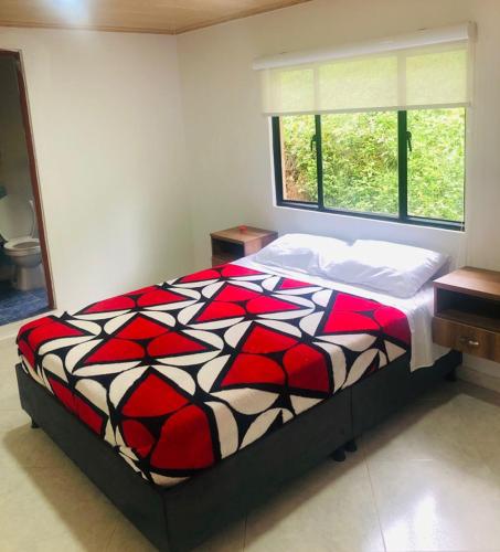 a bedroom with a bed with a red and black comforter at Cabañas Avani in San Francisco