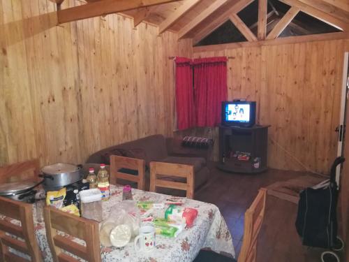 ein Wohnzimmer mit einem Tisch und einem TV in der Unterkunft Cabaña en linares camino el embalse ancoa in Linares