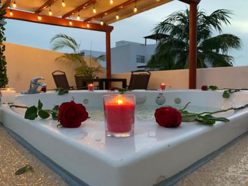 a candle sitting on a bath tub with two roses at Villa&Roofgarden -Jacuzzi privado- Relax&Confort in Acapulco