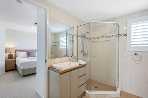 a bathroom with a sink and a shower and a bed at Incredible Beachside Penthouse-RIVA11 in Mooloolaba