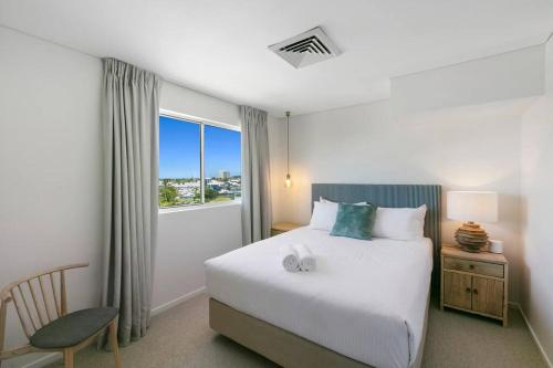 a bedroom with a bed and a chair and a window at Incredible Beachside Penthouse-RIVA11 in Mooloolaba