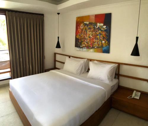 um quarto com uma cama branca e uma pintura na parede em Soda Resort Gili Trawangan em Gili Trawangan