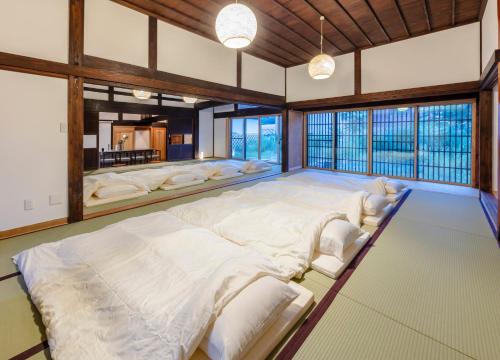 1 cama blanca grande en una habitación con ventanas en まるごの宿-耕-, en Sukagawa