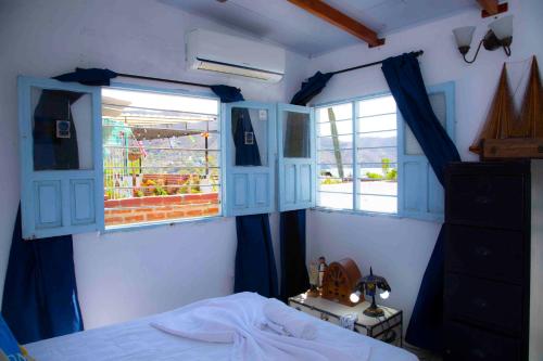1 dormitorio con ventanas con persianas azules y 1 cama en Casa remedios la bella, en Santa Marta