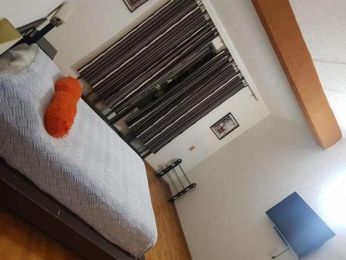 an orange pillow on a bed in a room with a window at Residencia paraíso in Temixco