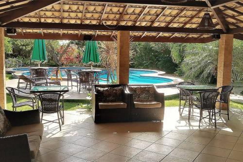 un patio con tavoli, sedie e piscina di Imbassai - Casa Alto Padrão completa - Condominio Fechado - A2B1 a Imbassai
