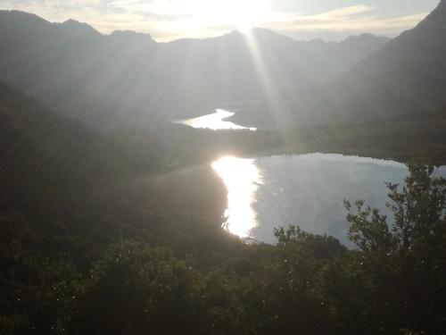 una vista de un lago con el sol brillando en él en Cabañas Serendipia Bariloche en San Carlos de Bariloche