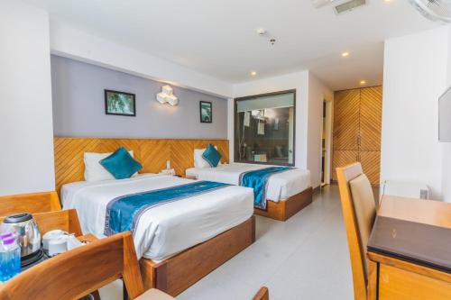 a bedroom with two beds and a table and a desk at Venue Hotel Nha Trang in Nha Trang
