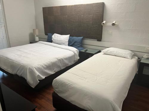 two beds in a hotel room with white sheets at Bungalow Hotel in Cairns