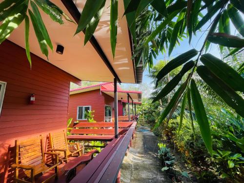 a red building with wooden benches on a porch at Lok Mun Bungalows in Ko Yao Noi