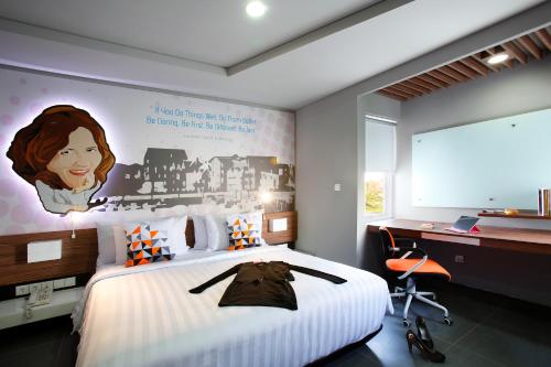 a bedroom with a large bed with a picture on the wall at Berry Biz Hotel Sunset Road in Seminyak