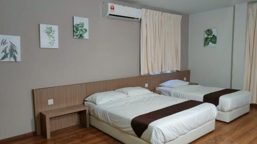 a bedroom with two beds and a window at Yew Hotel in Miri