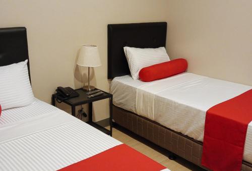 a room with two beds and a table with a lamp at Central District Hotel Davao in Davao City