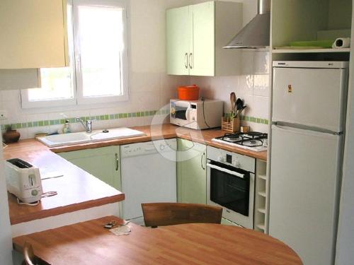une cuisine avec des armoires vertes et un réfrigérateur blanc dans l'établissement Maison 4 pers avec jardin privé et parking, proche mer - Angles - FR-1-357-6, à Angles