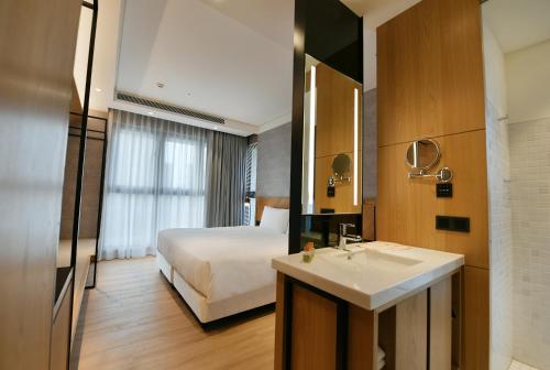 a bathroom with a bed and a sink in a room at CHECK inn Select New Taipei Sanchong in Taipei