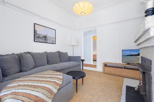 a living room with a gray couch and a tv at Boatshed and Boathouse in Huskisson