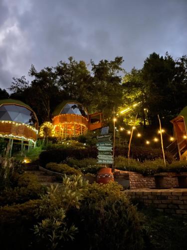 a building with two domes in a garden at night at Glamping Domos del Lago in Aquitania