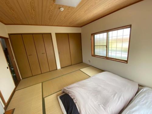 弘前的住宿－HIROSAKI清水森はうす，一间卧室设有一张床和一个窗口