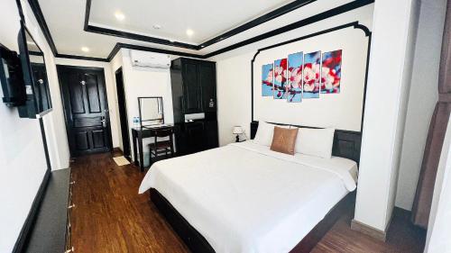 a bedroom with a white bed and a painting on the wall at Phuong Dong Hotel and Apartment in Quy Nhon