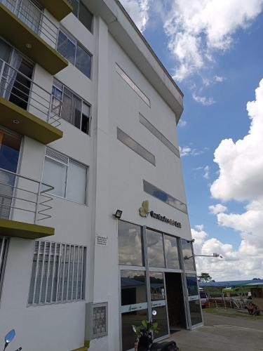 a white building with a motorcycle parked in front of it at Apartamento Aroma de Café in Montenegro