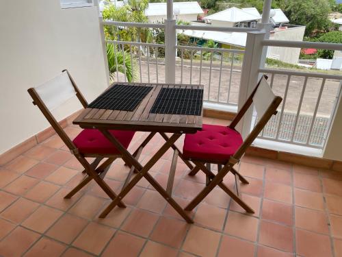 stół i 2 krzesła z laptopem na balkonie w obiekcie CLANES LOCATION Acerola w mieście La Trinité