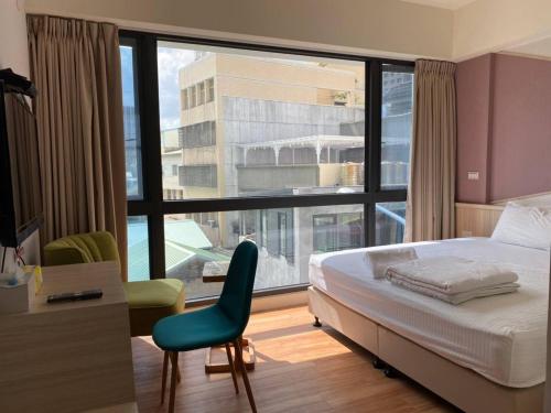 a bedroom with a bed and a chair and a large window at IF Guest House in Tainan